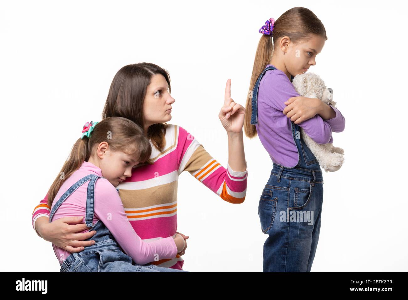 Mama schimpft Tochter, die ein Spielzeug von einem anderen Mädchen gestohlen Stockfoto