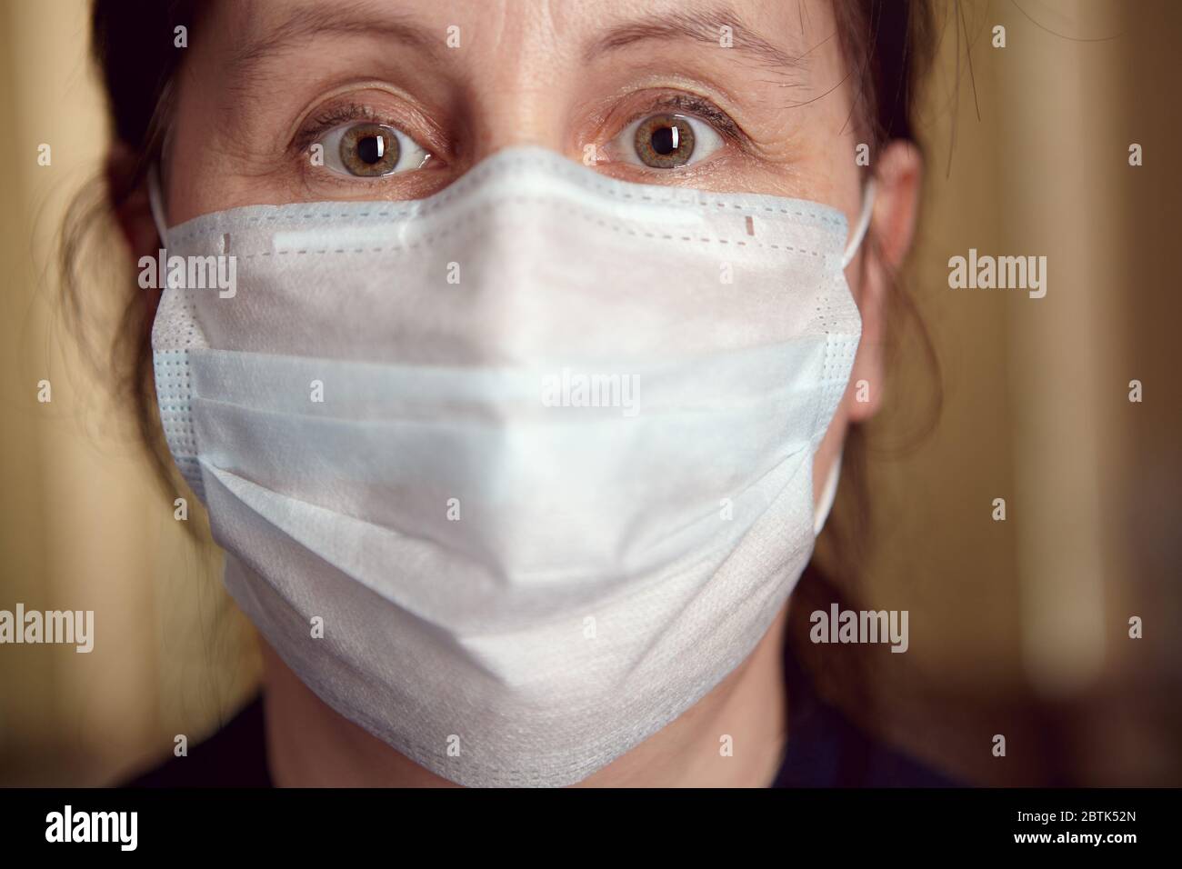 Bleiben Sie im Hinblick auf die COVID-19-Pandemie zu Hause. Weiße Frau im Gesicht Einweg medizinische Maske als Schutz vor Infektionen während der Selbstisolierung an Stockfoto