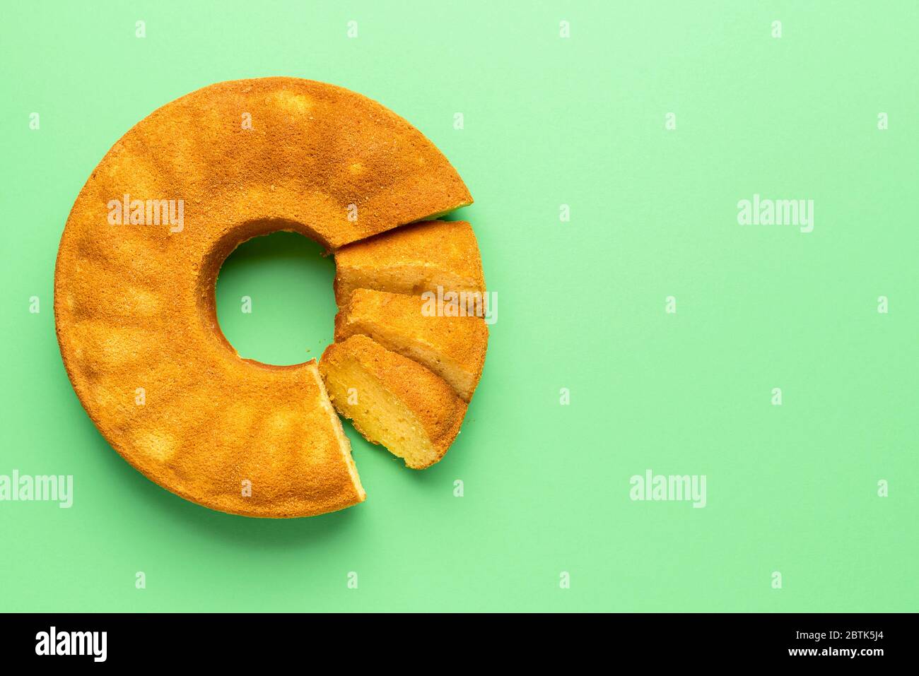 Portugiesischer Maismehlkuchen, in Scheiben geschnitten, auf grünem Hintergrund. Flacher Lay mit Festa Junina traditionellen Dessert. Brasilianischer Kuchen. Mais-Dessert. Stockfoto