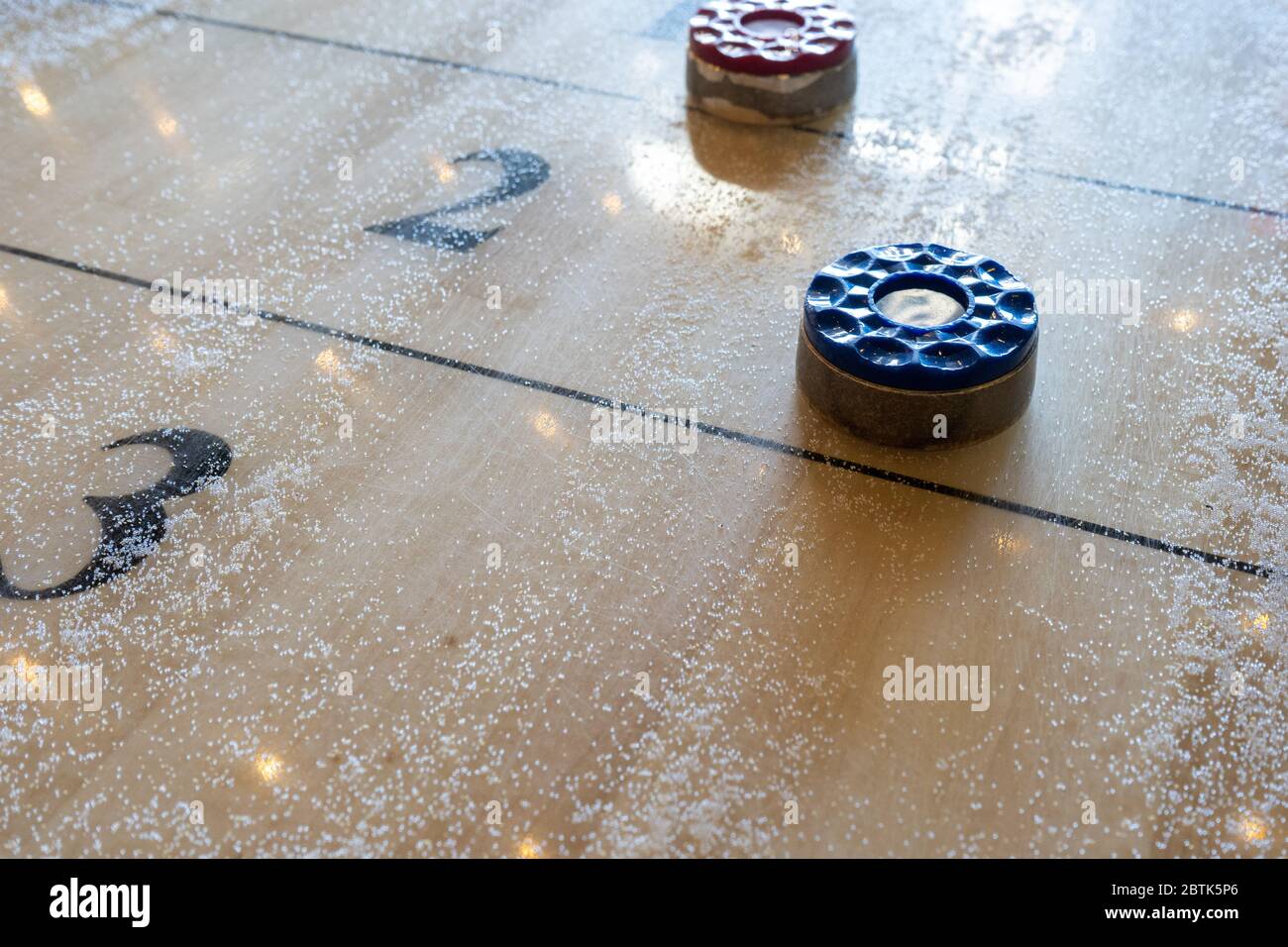 Rote und blaue Pucks auf einem Shuffleboard-Tisch. Stockfoto