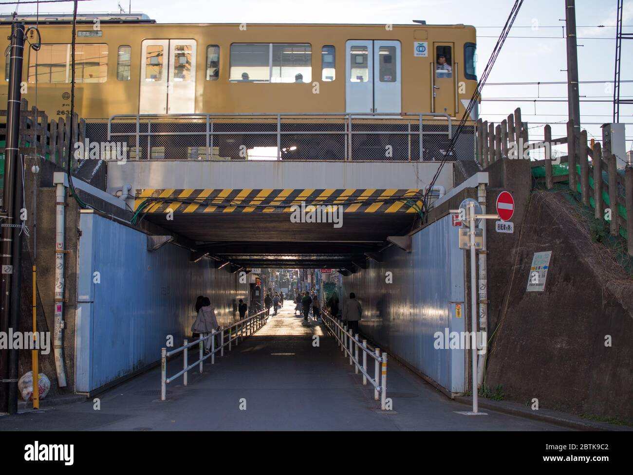 Eine Gasse in Shinjuku mit einem JR Chuo Line Zug, der oben vorbeifährt. Tokio, Japan Stockfoto
