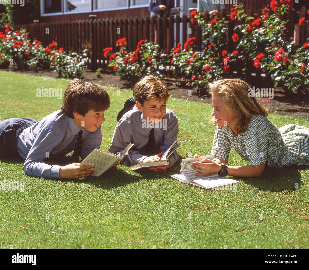 Schulkinder liegen auf dem Rasen in der Schule, Surrey, England, Großbritannien Stockfoto