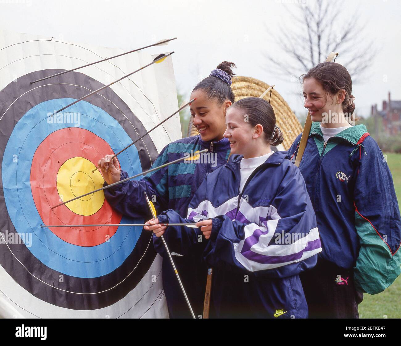 Student Mädchen Überprüfung Bogenschießen Ziel, Surrey, England, Vereinigtes Königreich Stockfoto