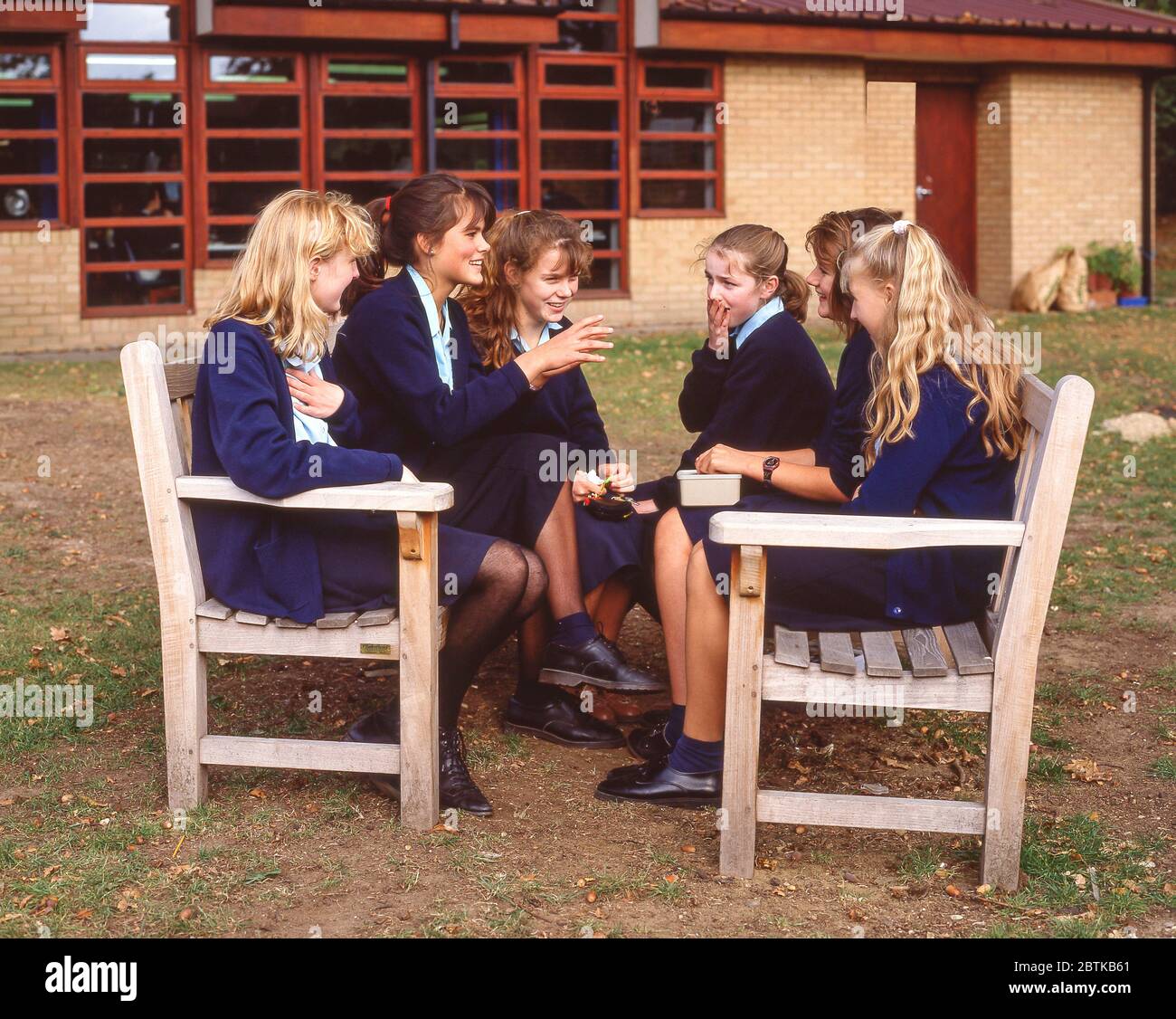 Schülerinnen plaudern mittags auf dem Schulgelände in Surrey, England, Großbritannien Stockfoto