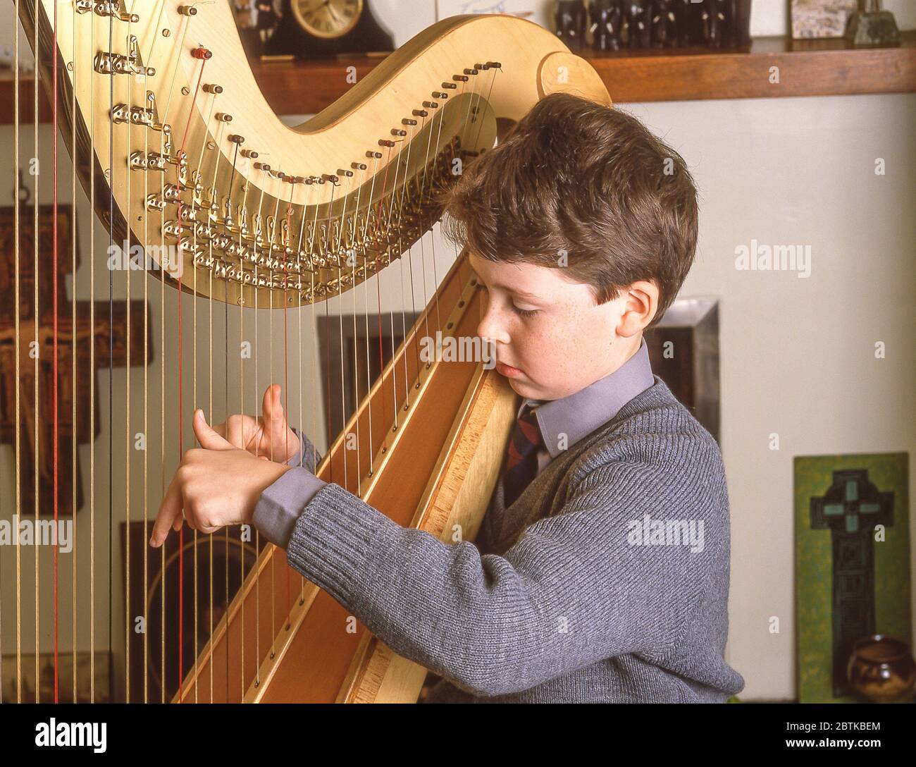 Schuljunge spielt Harfe Musikinstrument in der Schule, Surrey, England, Großbritannien Stockfoto