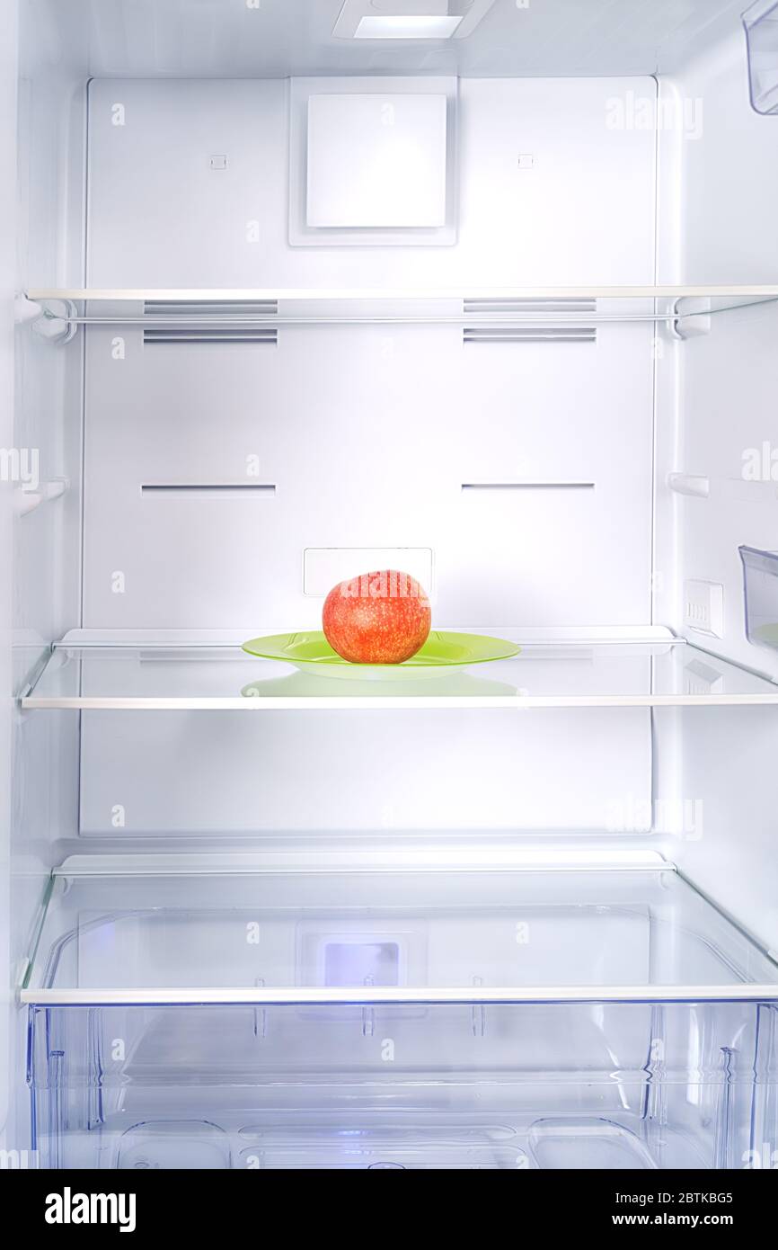 Leerer Kühlschrank mit rotem Apfel innen. Diät und Mangel an Essen Thema Stockfoto