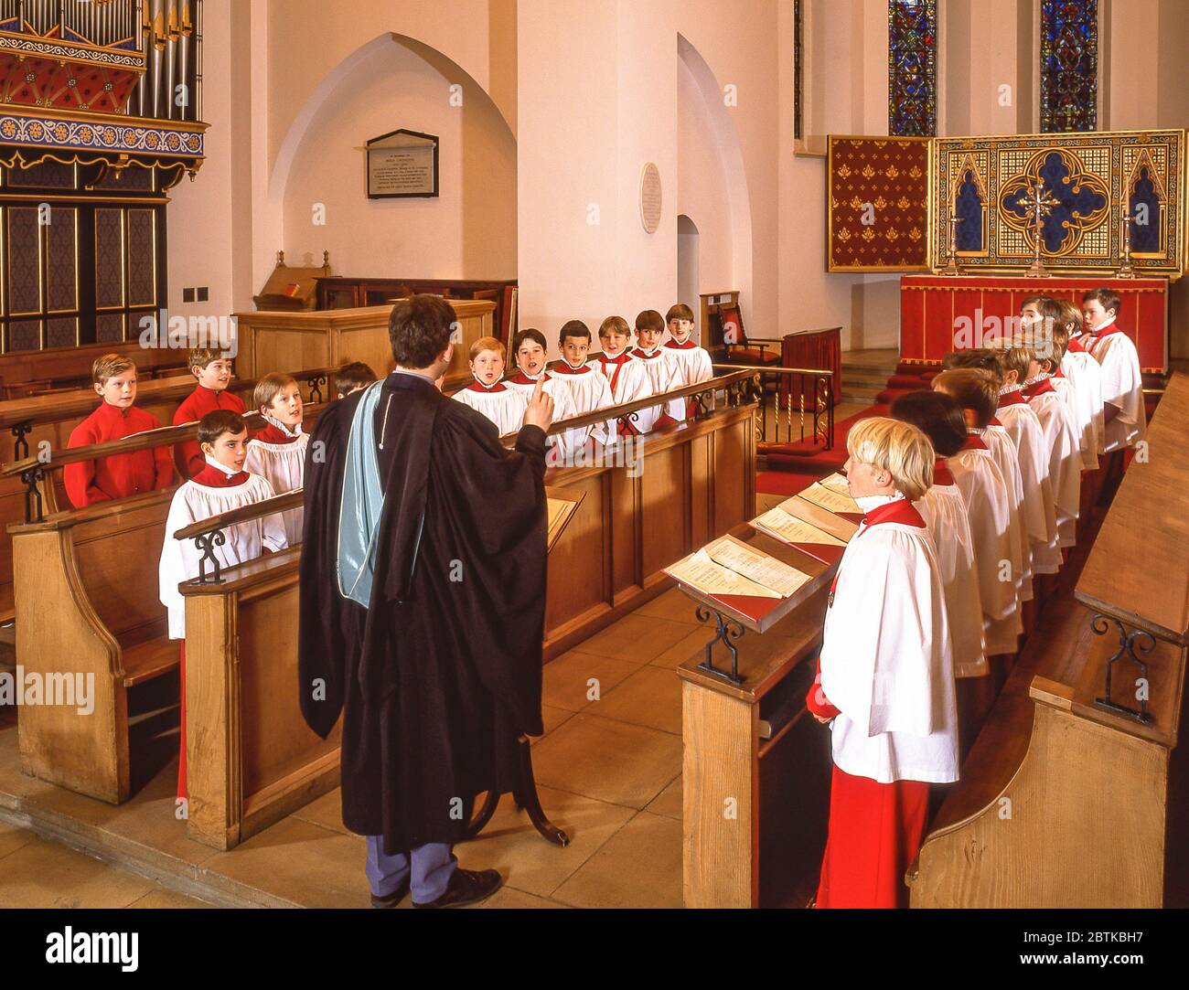 Chorleiter dirigiert Knabenchor in der Kirche, Surrey, England, Vereinigtes Königreich Stockfoto