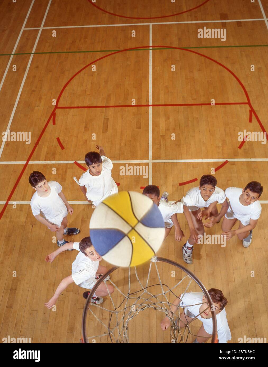 Jungen, die Basketball in der Schule Fitness-Studio, Surrey, England, Großbritannien Stockfoto