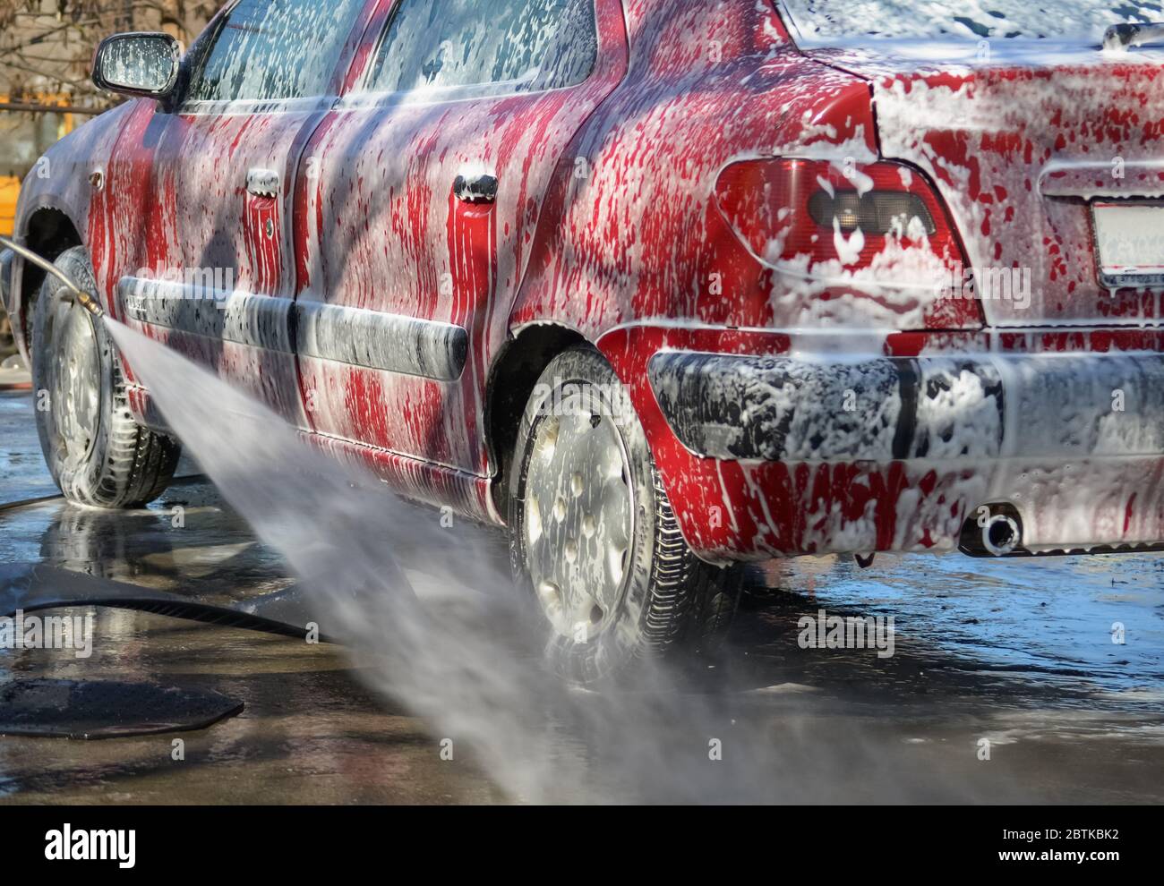 Mann, der ein Auto mit einem Hochdruckwasserstrahlkompressor wäscht Stockfoto