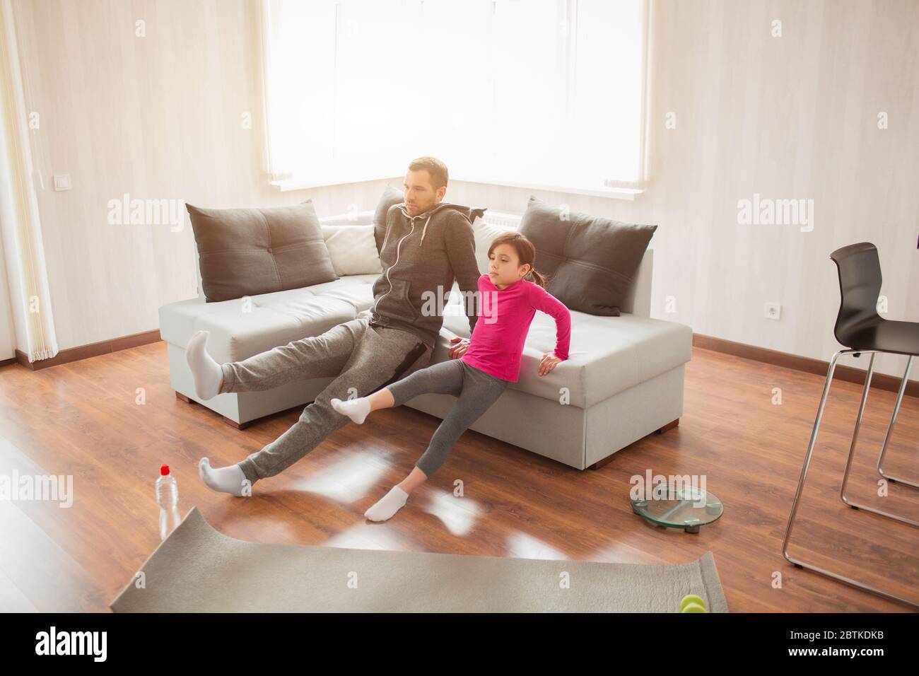 Vater und Tochter trainieren zu Hause. Training in der Wohnung. Sport zu Hause. Reverce Plank mit Bein heben auf dem Boden zu Hause. Stockfoto