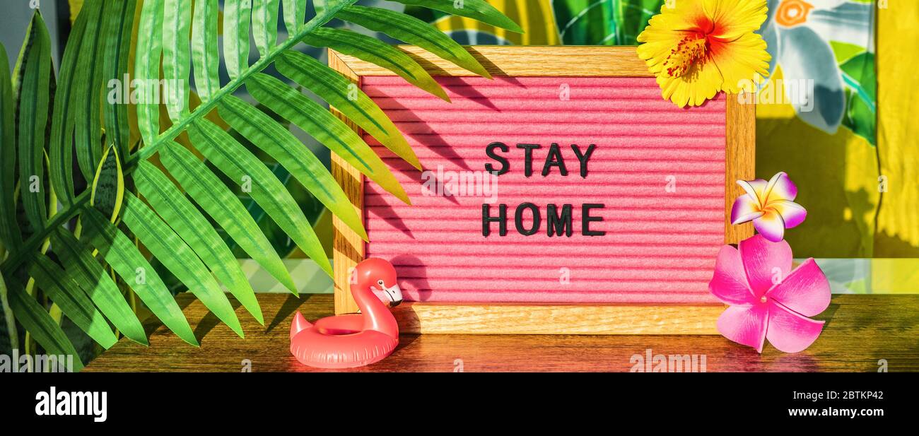 BLEIB ZUHAUSE Zeichen für Sommerurlaub Pläne während COVID-19 Reiseverbot. Tropischer Hintergrund mit Palmenblättern, Blumen, Flamingo-Pool treiben. Stockfoto