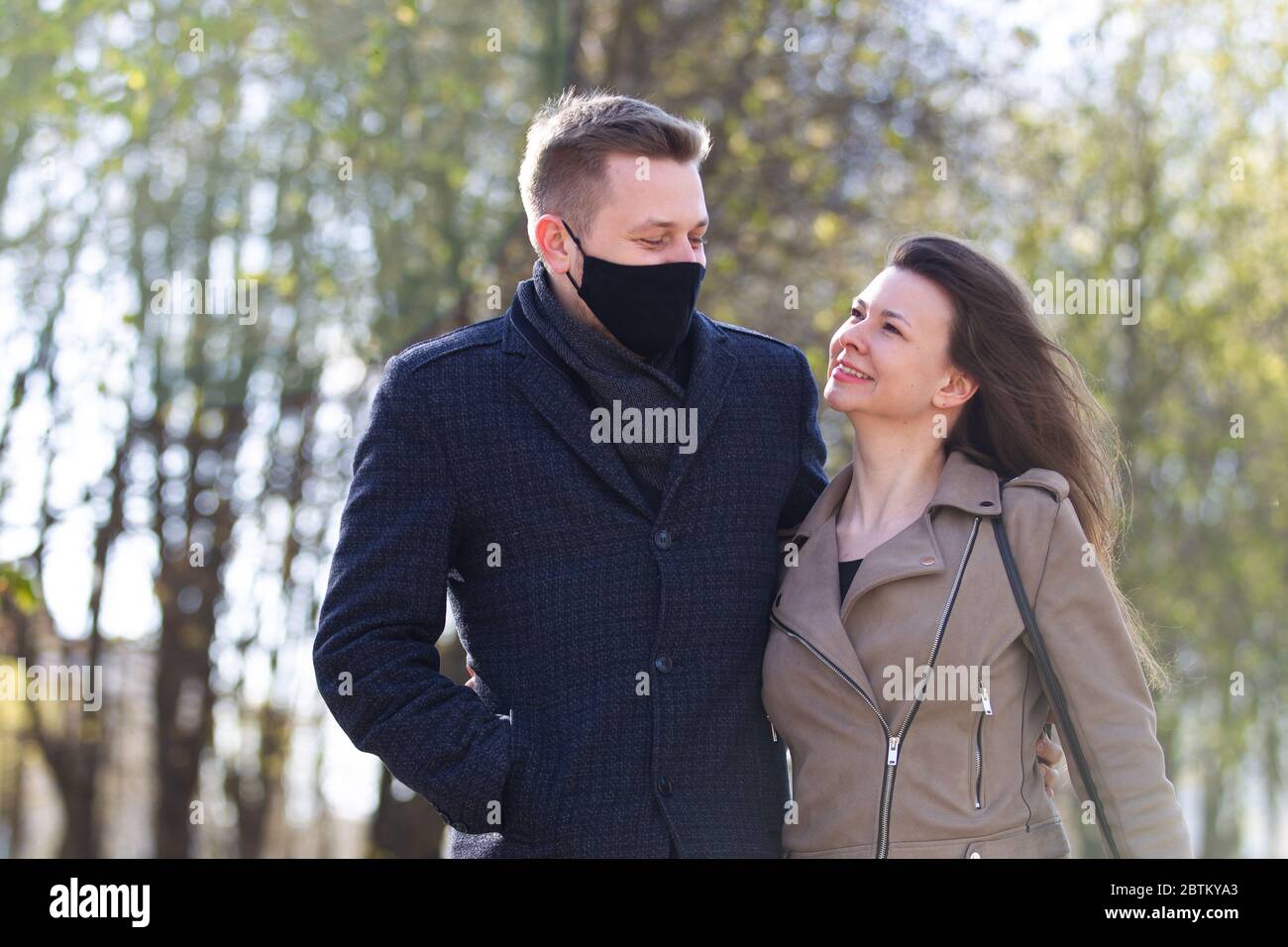 Maskiertes Paar, das im Park draußen spazieren geht Stockfoto