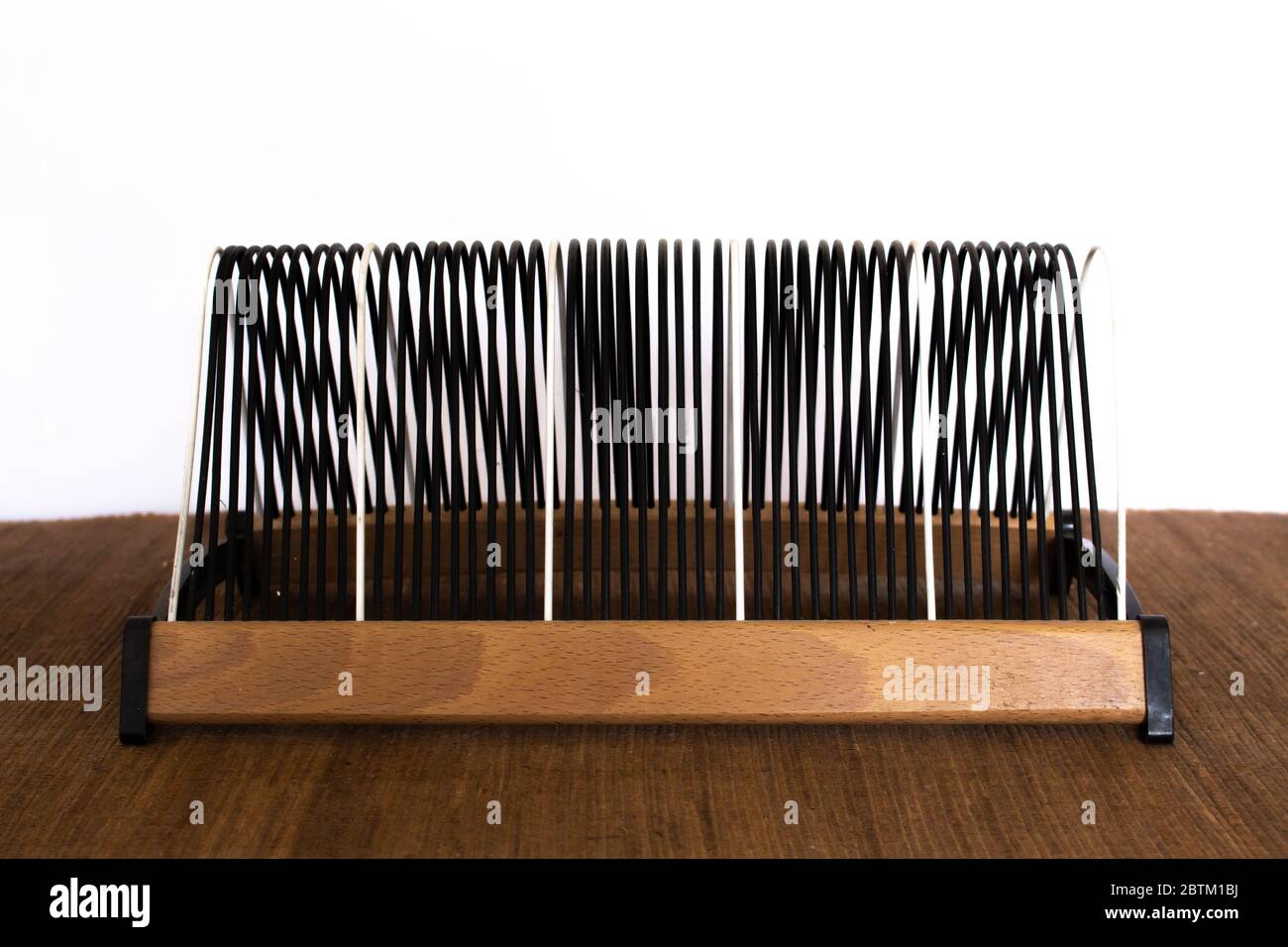 Leeres Vintage schwarz-weißes Drahtgestell mit Holzsockel für klassische alte 45 Vinyl Schallplatten Stockfoto