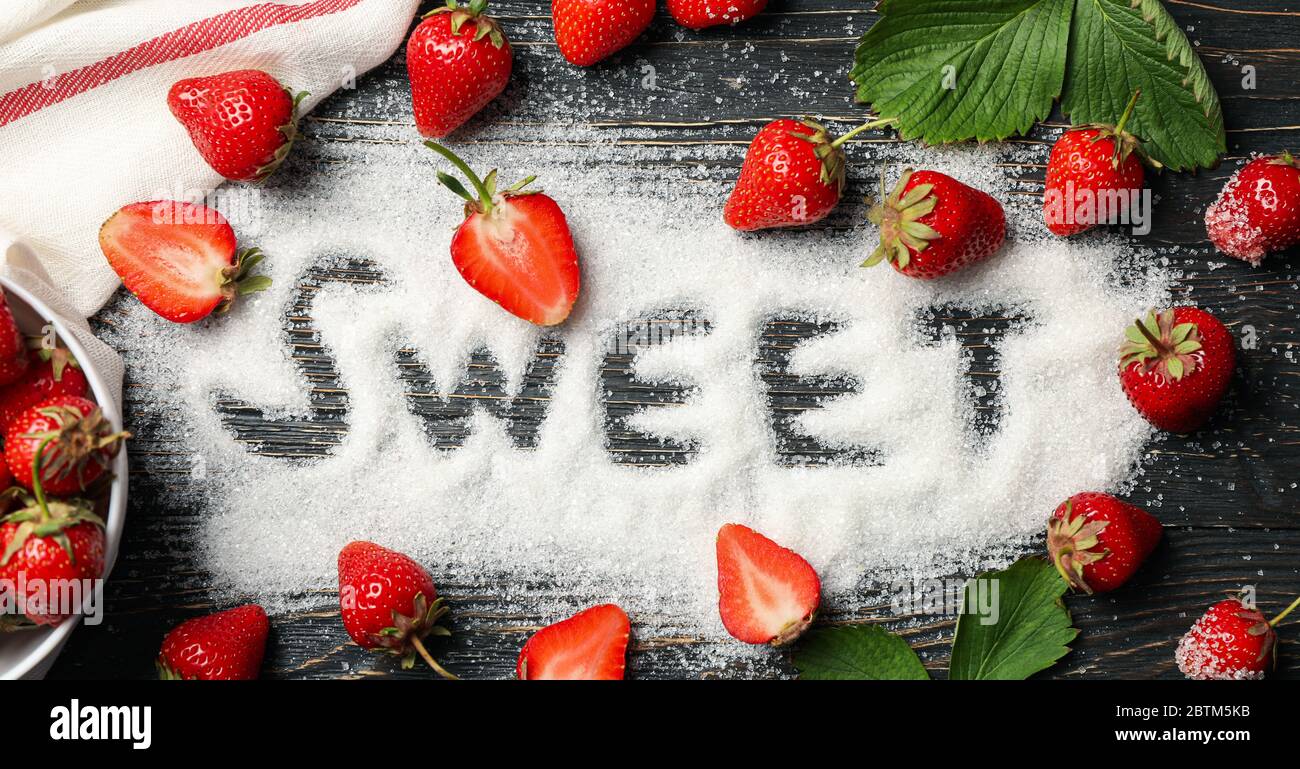 Word Sweet aus Zucker und Erdbeere auf Holzhintergrund, Draufsicht. Sommerbeere Stockfoto