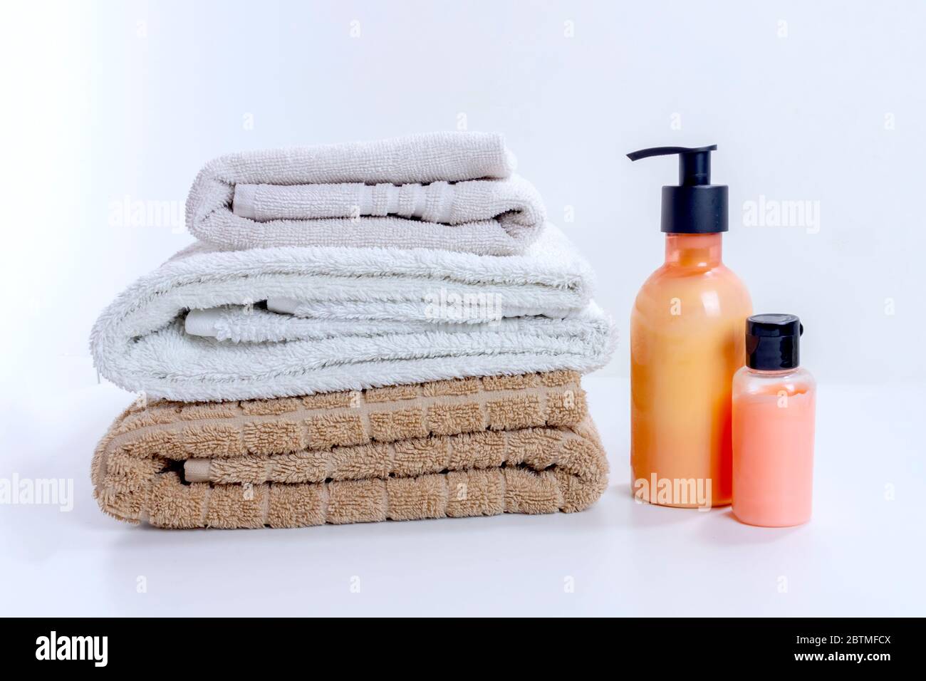 Stapel von sauberen Handtüchern mit Creme und Lotion für Dusche und Bad Behandlung. Home Spa und Entspannung convept auf weißem Hintergrund Stockfoto