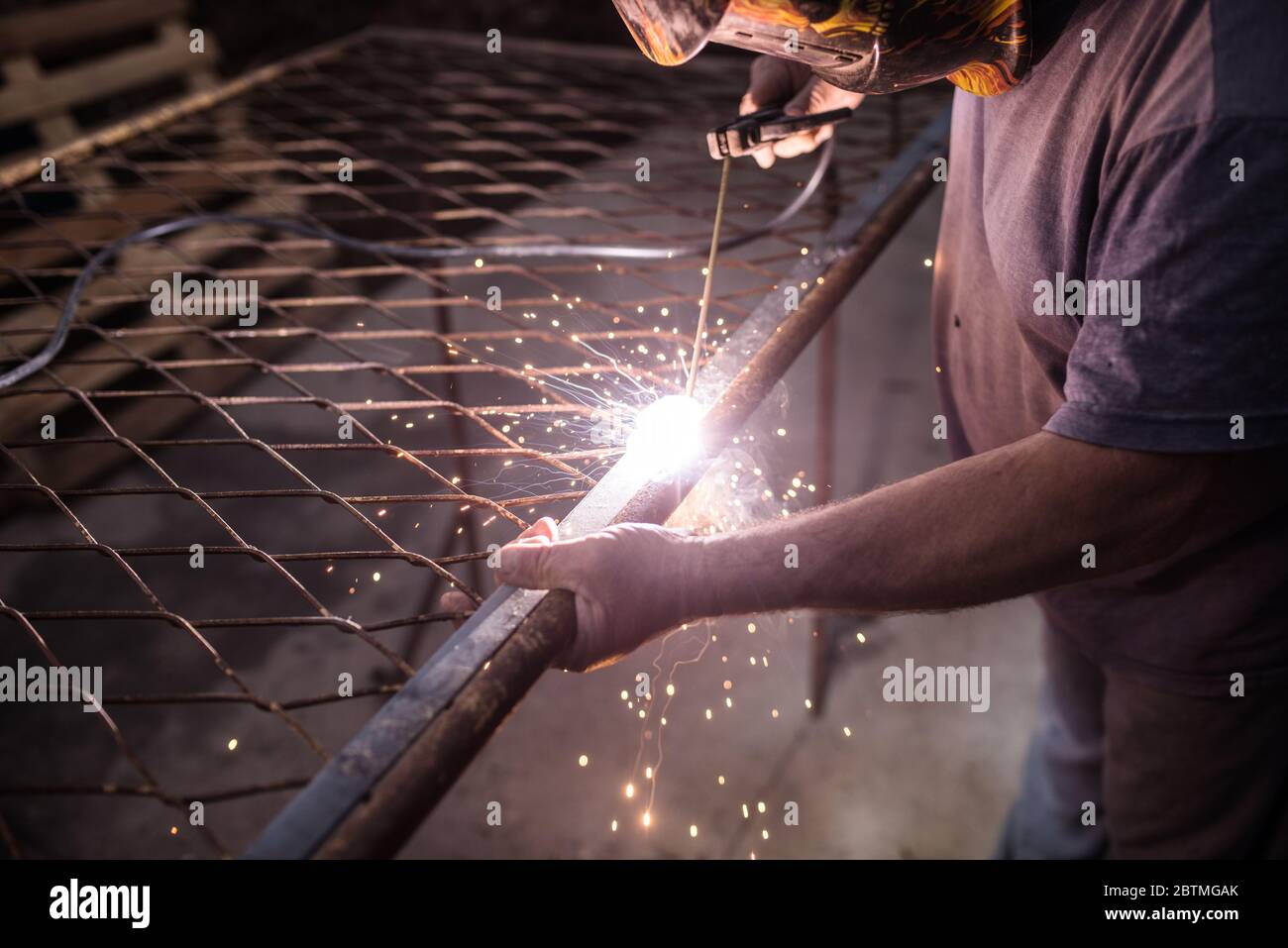 Schweißer mit Schutzmaske Schweißen von Stahlkonstruktionen und hellen Funken in der Bauindustrie Stockfoto