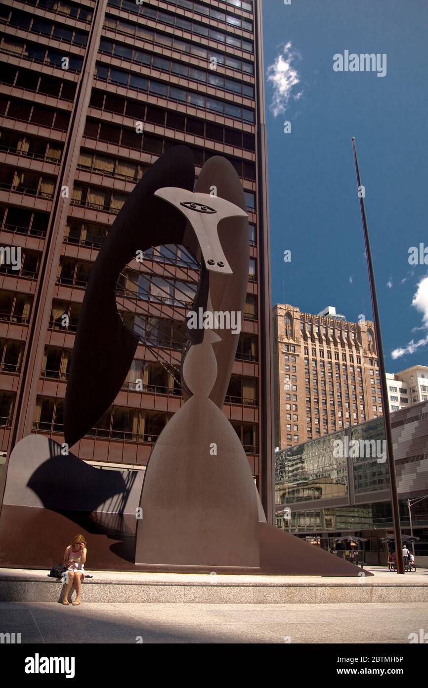 Vertikale Ansicht einer Frau, die vor der Picasso-Skulptur ohne Titel auf dem Daley Plaza in Chicago Loop, Illinoi, USA sitzt Stockfoto