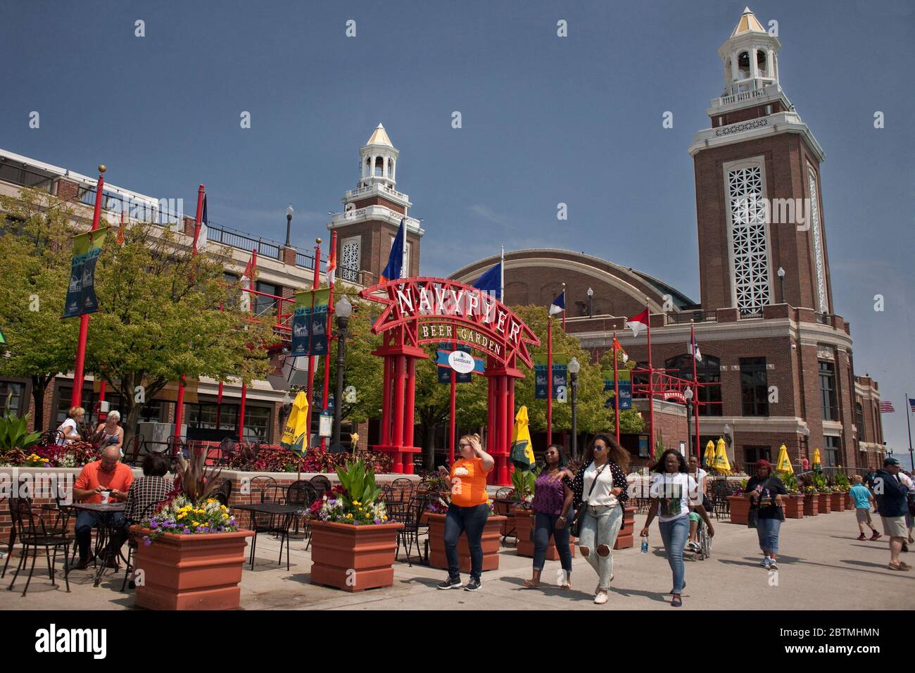 Horizontale Aufnahme von vier Mädchen, die am Miller Lite Beer Garden vorbeikommen, mit dem Aon Grand Ballroom im Hintergrund, Navy Pier an einem sonnigen Tag, Chicago Stockfoto