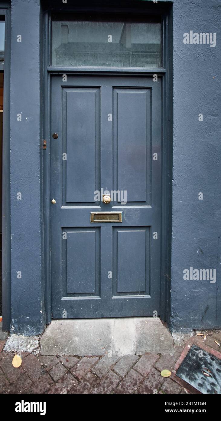 Blaue Tür mit vier Paneele, Heckspiegel, Briefkasten und Türknopf in der Mitte in Irland. Vertikales Format. moody, Geheimnis, offen, geschlossen, Durchgang, betreten. Stockfoto