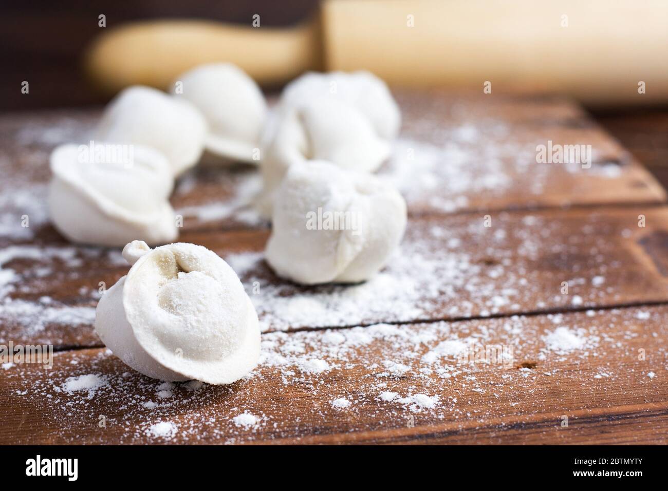 Rohe hausgemachte Pelmeni (Knödel) mit Fleisch auf Holzhintergrund. Stockfoto