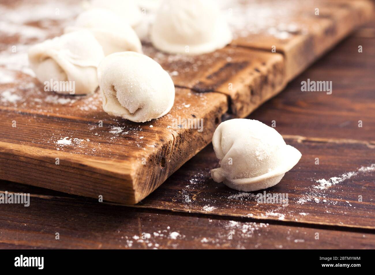Rohe hausgemachte Pelmeni (Knödel) mit Fleisch auf Holzhintergrund. Stockfoto