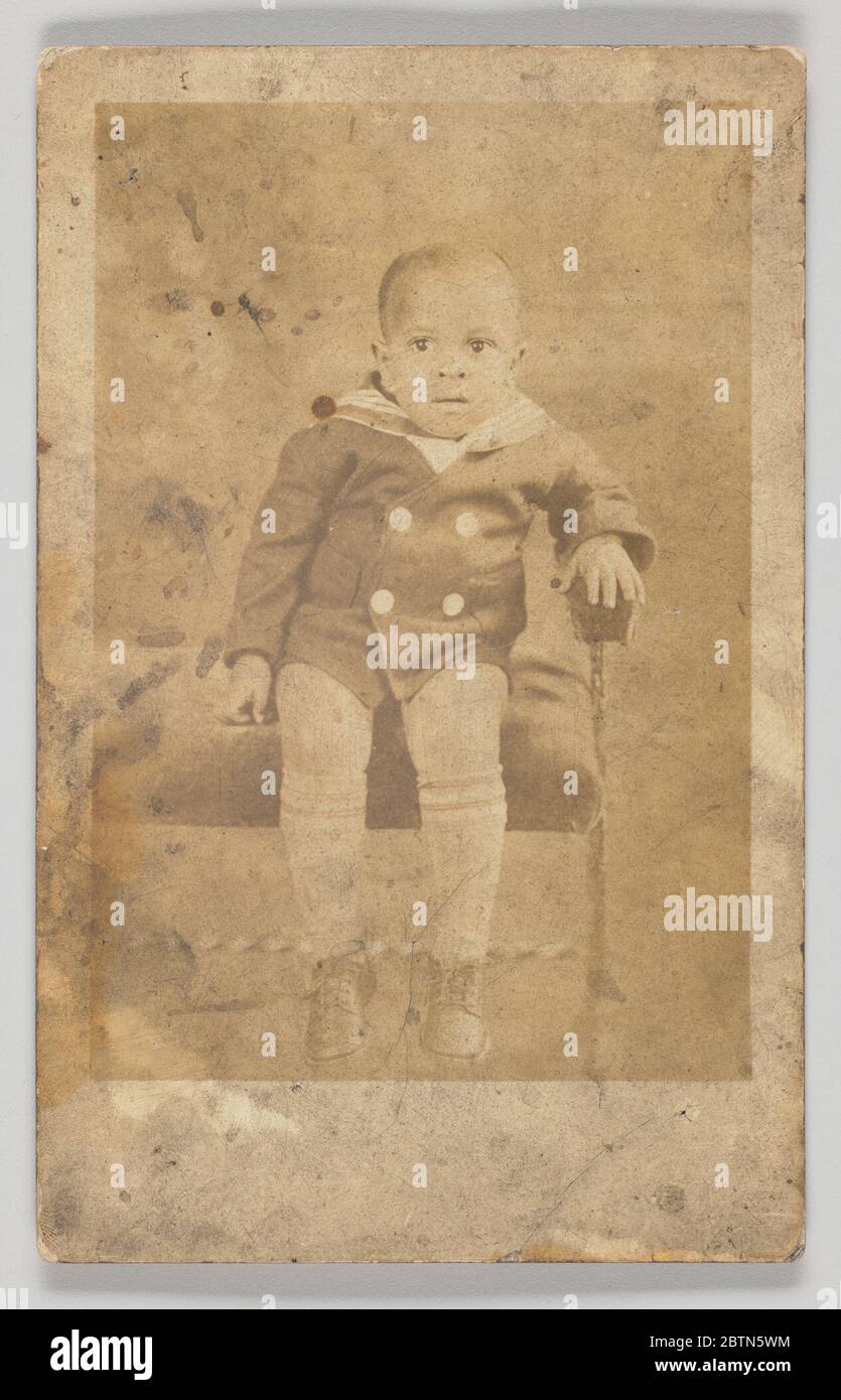 Fotopostkarte eines unbekannten Jungen. Eine Fotopostkarte eines unbekannten Jungen in einer Seemannsuite. Der Junge sitzt auf einer Bank, der linke Arm ruht auf dem Arm der Bank. Stockfoto