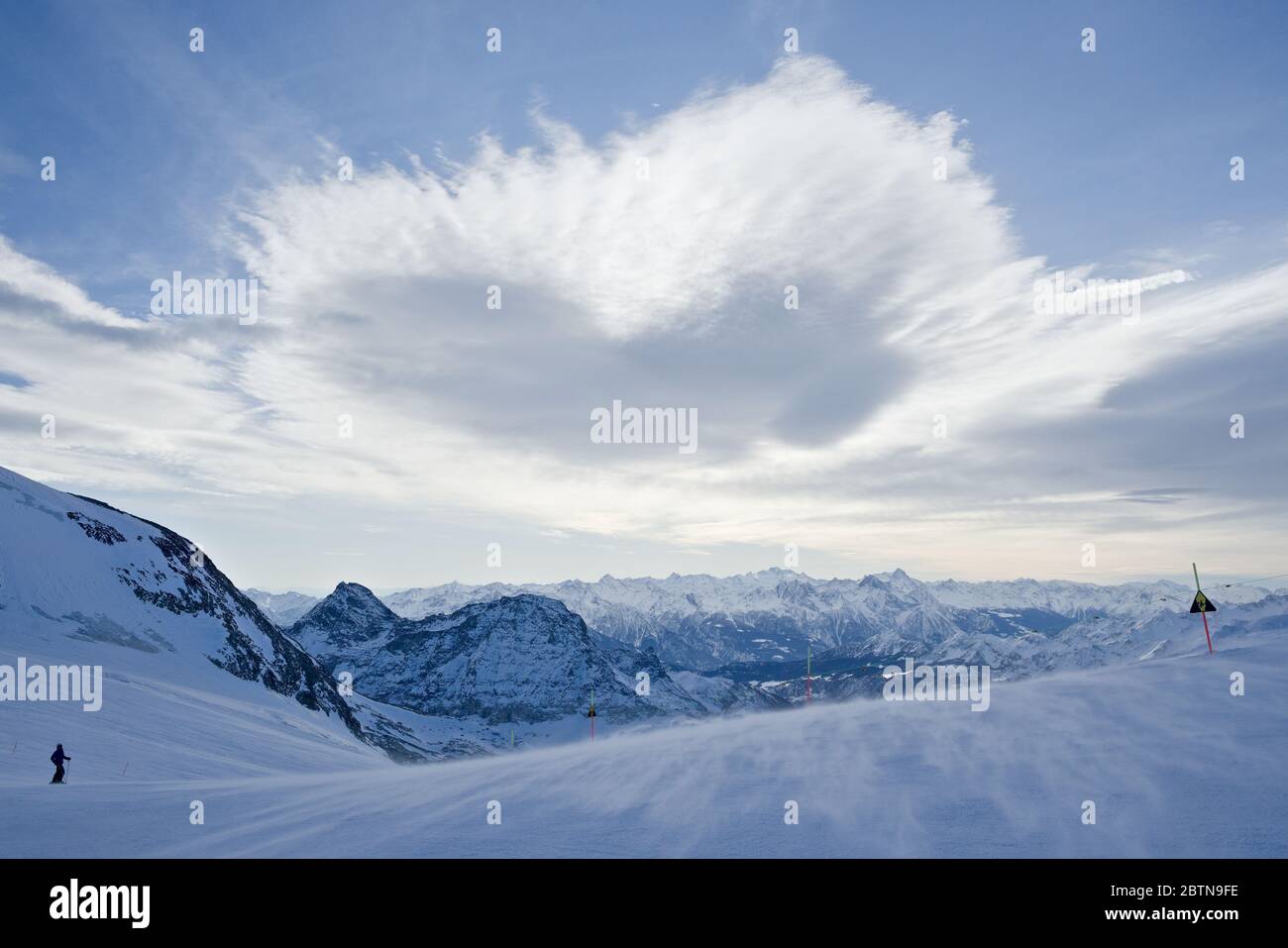 Eine herzförmige Wolke schwebt über einer Skipiste als Teil einer weitläufigen bergkulisse in den italienischen alpen Stockfoto