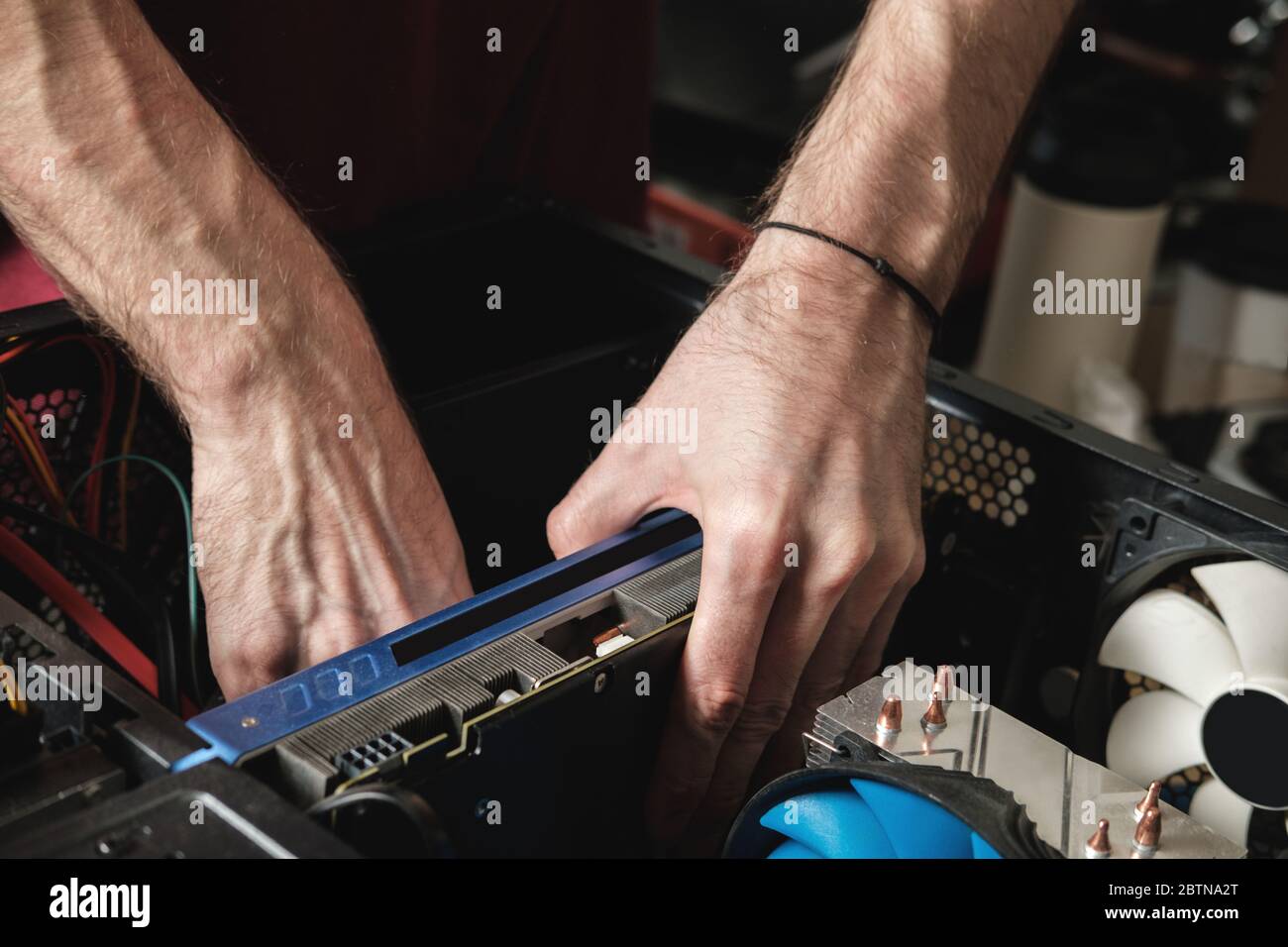 Mann repariert eine Computersystemeinheit, wechselt Teile, Grafikkarte und Festplatte. Assistent Für Computerreparaturen Stockfoto
