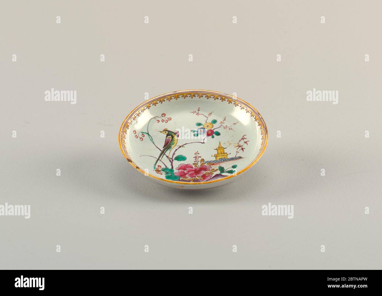 Untertasse mit Vogelblumen und Pagode. Forschung in ProgressUntertasse von rosa Buff Ton mit gräulicher Glasur. Polychrome Malerei des Vogels mit langem Schwanz auf blühenden Baum Zweig Blumen und Pagode. Am Rand, gelbe und braune Linien, das Innerste zu Trifoils erweitert. Stockfoto