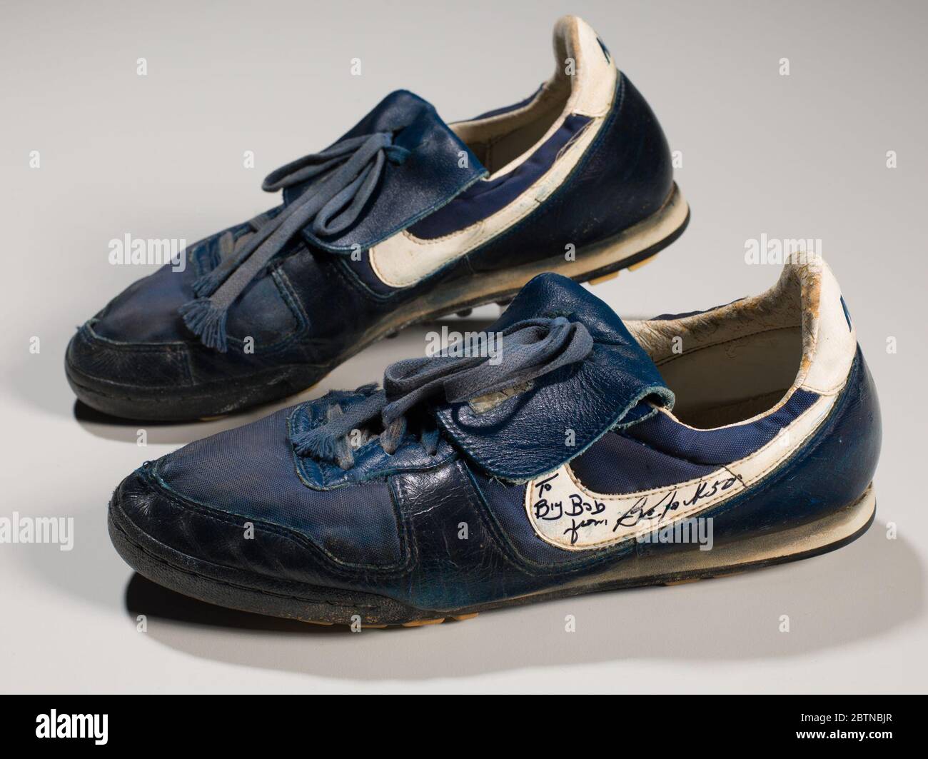 Schuhe getragen und signiert von Bo Jackson. Ein Paar dunkelblaue Sportschuhe, die von Bo Jackson getragen werden. Die Schuhe haben weiße Akzente, darunter ein weißes Nike Logo an der Seite der Schuhe. Auf der Rückseite der Schuhe steht blau: [NIKE]. Handschriftlich auf den Fersen des Schuhs ist: [BO]. Stockfoto