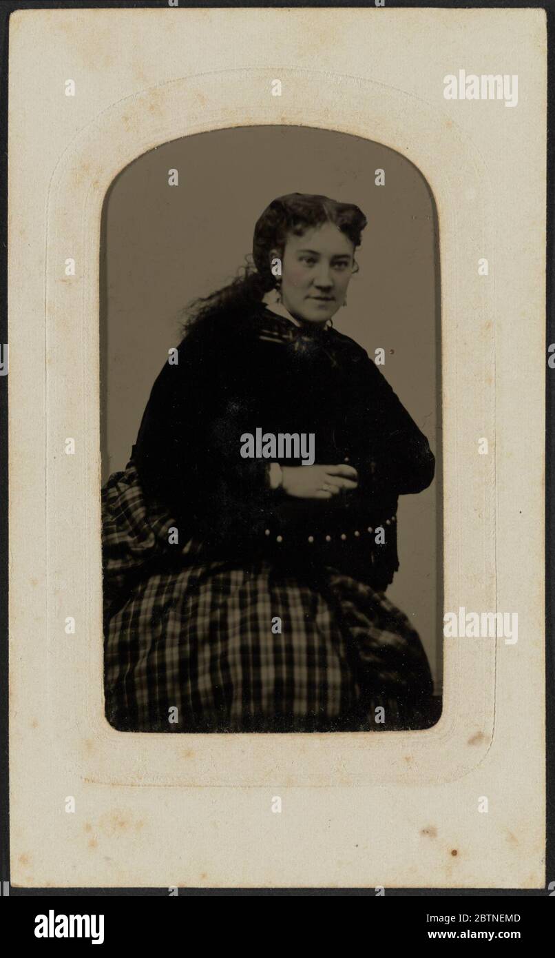 TinType Porträt von Frau Annie Cox. TinType von Frau Annie Cox in drei Viertel Porträt gezeigt. Cox sitzt und lehnt sich mit gekreuzten Armen auf den Arm eines Stuhls. Sie ist leicht nach links gedreht und schaut vom Rahmen weg. Stockfoto