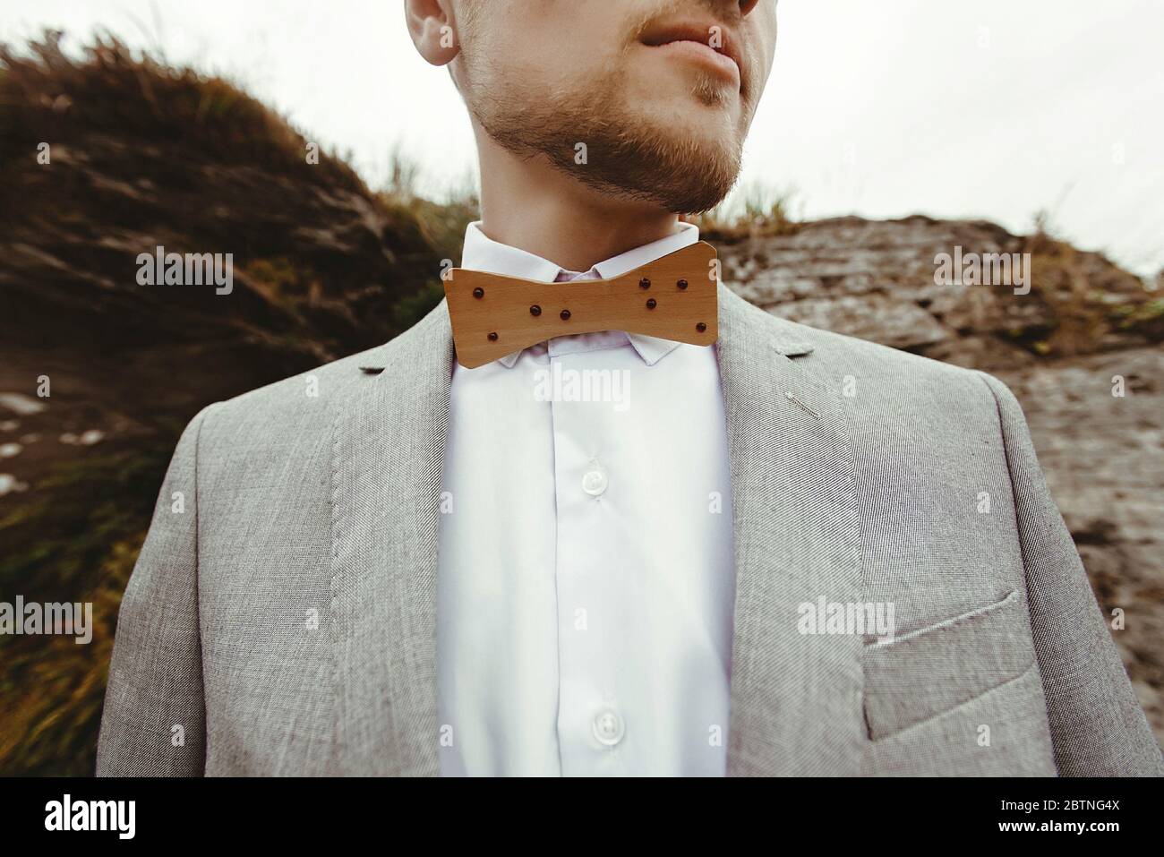 Stilvolle Holzschleife des Bräutigams, Nahaufnahme von Hintergrundfelsen in den Bergen, luxuriöse Boho-Hochzeit Stockfoto