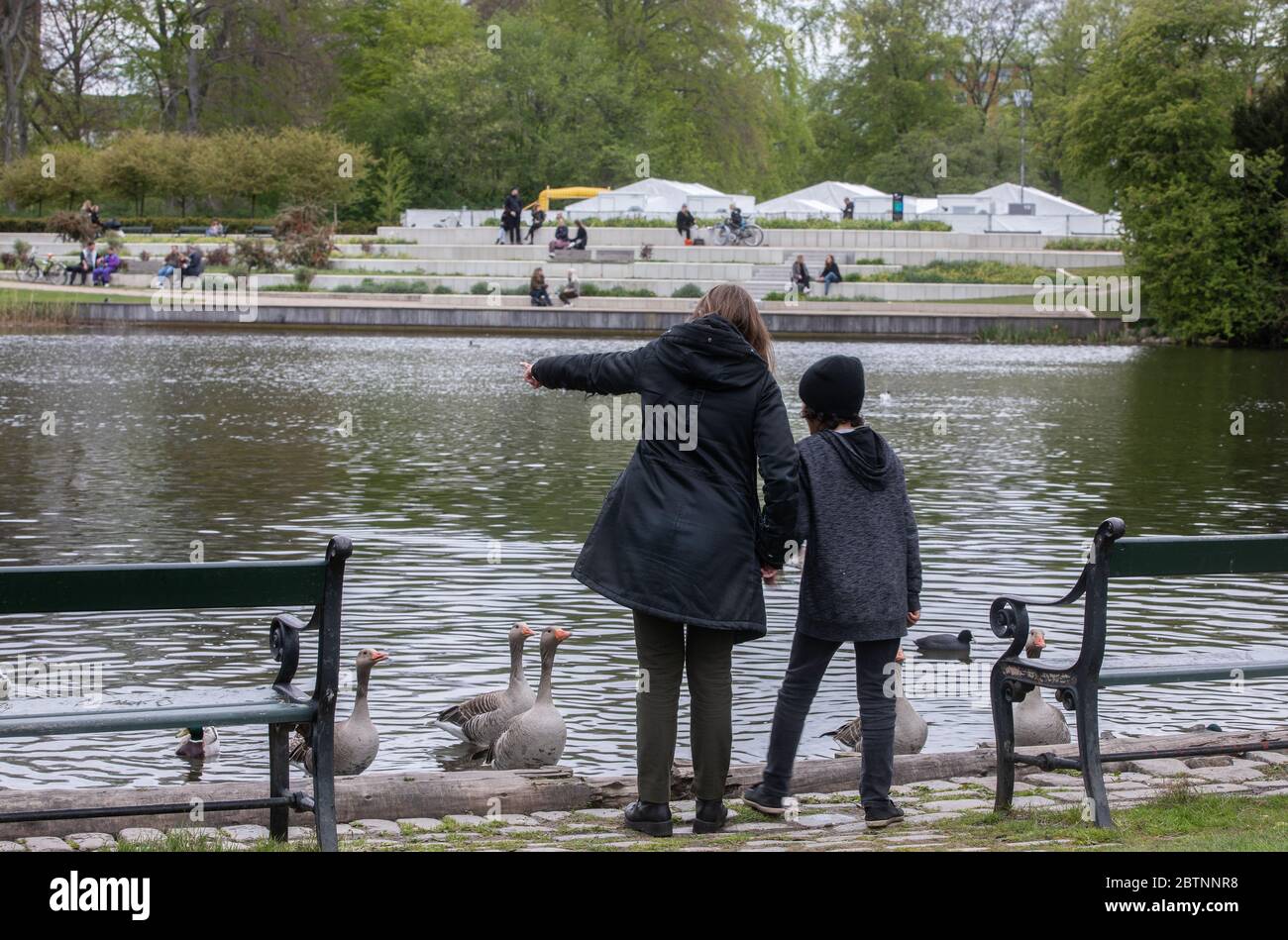 Mutter und Sohn beim Betrachtungs-Blick auf Vögel in einem Kopenhagener Park neben dem temporären Covid-19 Testzentrum Stockfoto