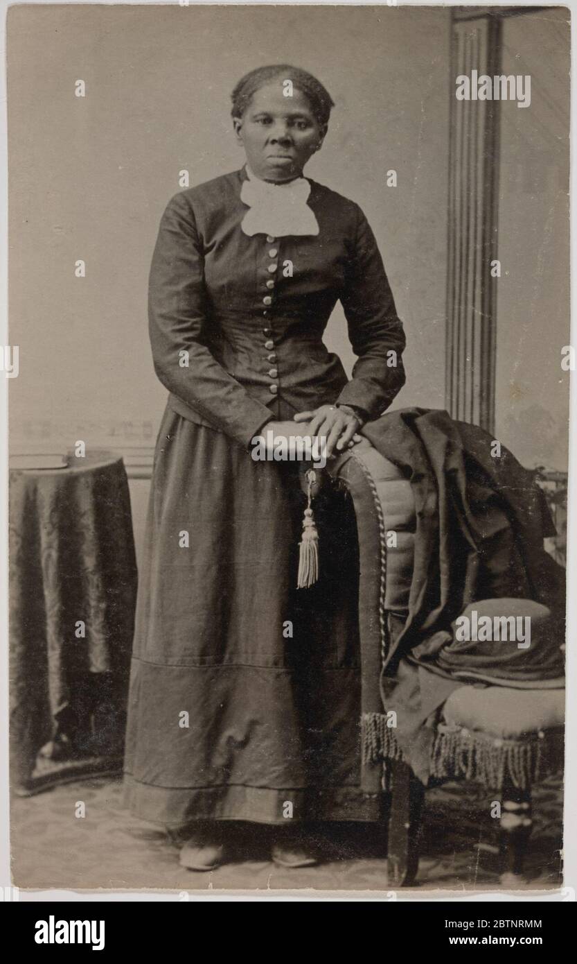 Matter Kollodiondruck von Harriet Tubman. Matte Kollodionaufnahme von Harriet Tubman, die in einem InnenraumSetting steht. Das Porträt zeigt Tubman in der Mitte des Rahmens, der Fotografin gegenüber, wobei ihre Hände auf der Rückseite eines gepolsterten Stuhls ruhen. Stockfoto