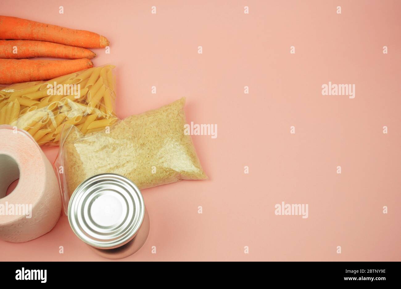 Lebensmittelversorgung Quarantäne Nahrungsmittelkrise isoliert auf rosa Hintergrund. Reis, Nudeln, Dosenfutter, Möhren, Toilettenpapier. Das Konzept der Lieferung von Lebensmitteln Stockfoto