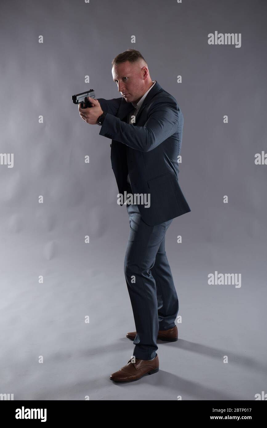 Bild eines weißen, männlichen, verdeckten Polizisten mit einer Pistole auf einem schlichten Hintergrund. Ideal für einen Action-Thriller, Krimi-Thriller Buch oder eBook Cover Design. Stockfoto