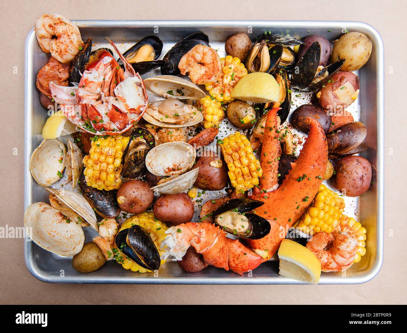 Venusmuscheln backen mit Venusmuscheln, Krabbenbeinen, Hummerkrallen, Muscheln, Kartoffeln, Mais und Gewürzen Stockfoto