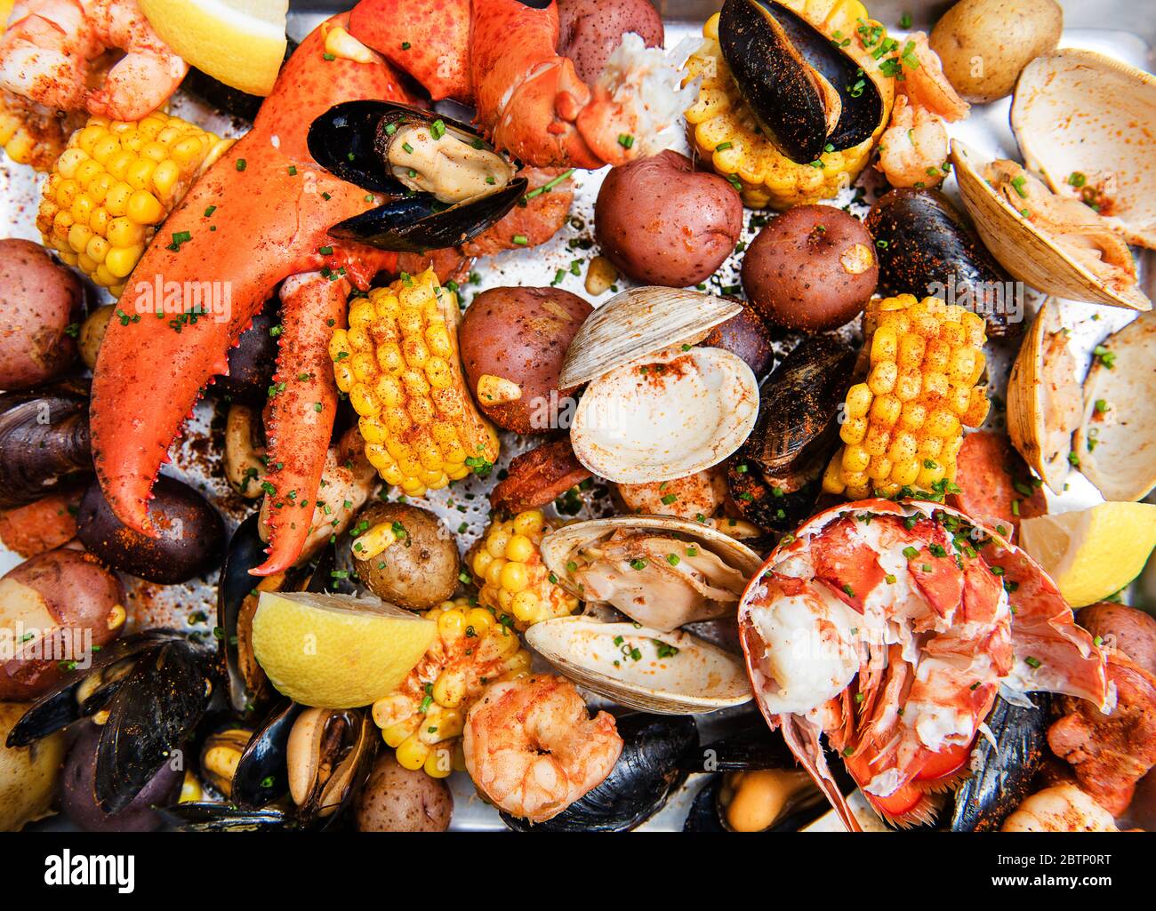 Venusmuscheln backen mit Venusmuscheln, Krabbenbeinen, Hummerkrallen, Muscheln, Kartoffeln, Mais und Gewürzen Stockfoto