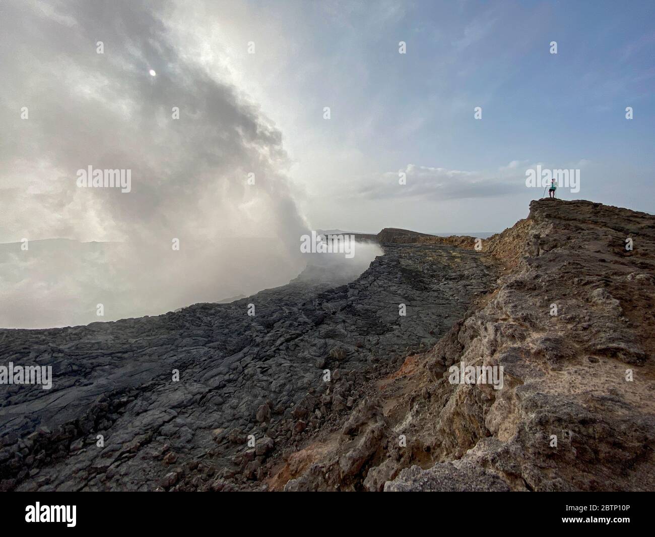 Wanderer auf Felsen Blick auf Rauch aus Erta Ale Vulkan, Danakil Depression, Afar Region, Äthiopien, Afrika Stockfoto