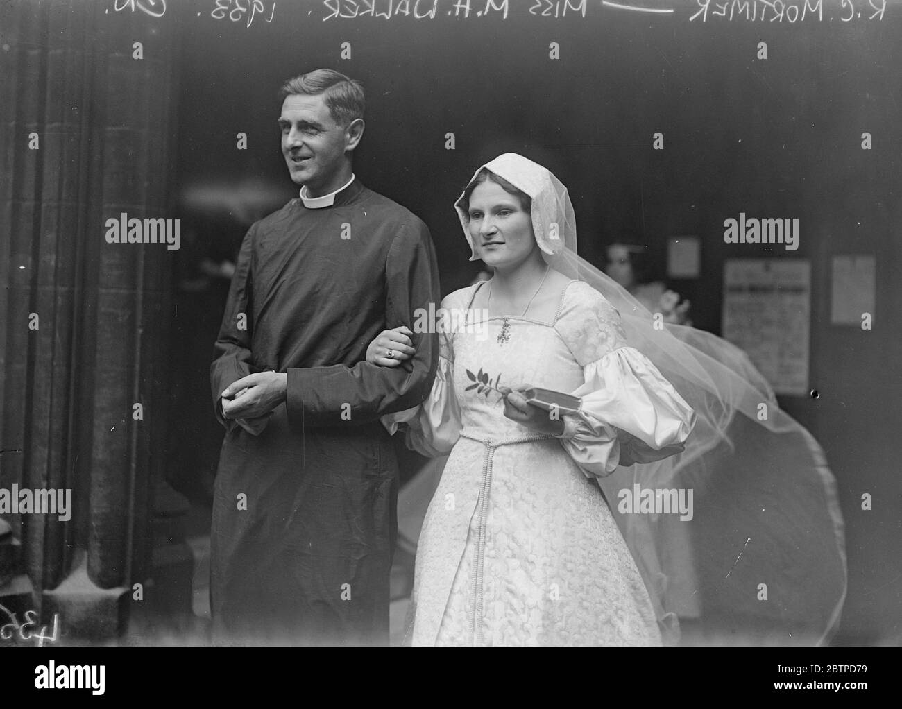 Eine klerikale Hochzeit . Die Ehe der Rev R C Mortimer und Miss M H Walker in St Mary Abbot 's, Kensington. Die Braut und der Bräutigam verlassen die Kirche. Die Braut trägt ein markantes mittelalterliches Kleid. 13 Juli 1933 Stockfoto