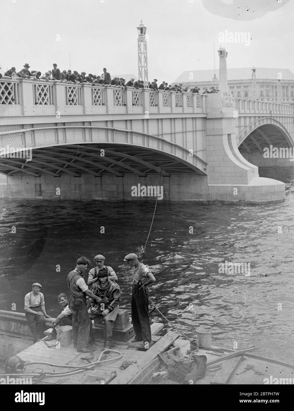 Tauchen in der Themse . Eine große Menge beobachtete einen Taucher Mr. W R Gloss, der zum Flussbett hinabkam, um Reste von Stahlpfählen zu entfernen, die in den Fluss nahe der neuen Lambeth-Brücke getrieben wurden, die in Kürze vom König eröffnet werden wird. Der Taucher Mr W R Gloss , nach dem Aufstieg aus dem Flussbett bei Lambeth . Juli 1932 Stockfoto