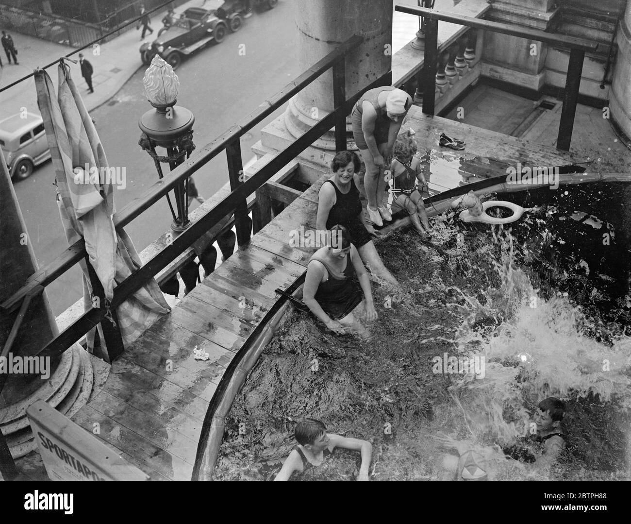 Baden über Piccadilly Verkehr. Auf dem terrassenbeeten Balkon des Piccadilly Hotels wurde ein Pool aufgestellt und die Badegäste tauchen direkt über dem Straßenverkehr ins Wasser. Badegäste im Pool über der Straße. August 1932 Stockfoto