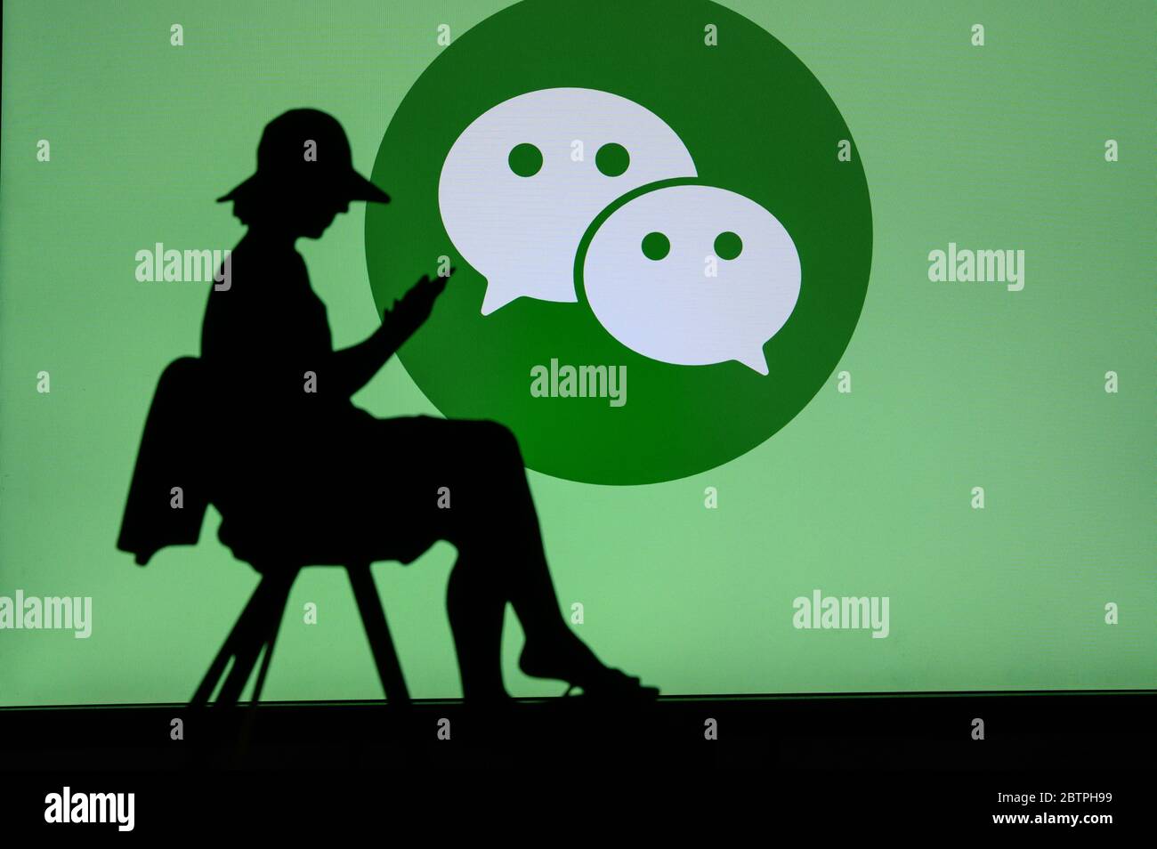 NEW YORK, USA, 25. MAI 2020: WeChat Chinesische Nachrichten, soziale Medien und mobile Zahlungs-App Junge Frau Silhouette auf dem Stuhl sitzen und spielen auf ihr Stockfoto