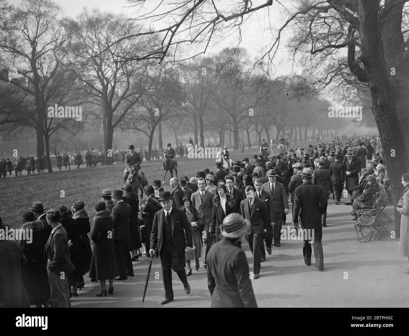 Frühling im Park . Eine normalerweise große Menge besuchte Hyde Park London, um den strahlenden Sonnenschein des ersten Frühlingssonntags des Jahres zu genießen. Menschenmassen im Hyde Park beobachten Reiter in der Sonne der Reihe . 20 März 1932 Stockfoto