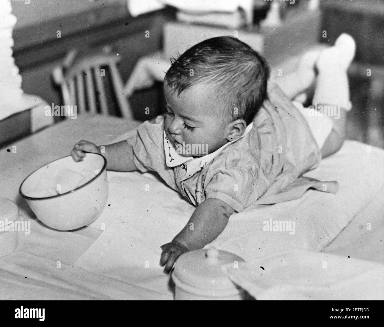 Dionne Quins . Cecile zeigt Interesse an der Schüssel. Stockfoto
