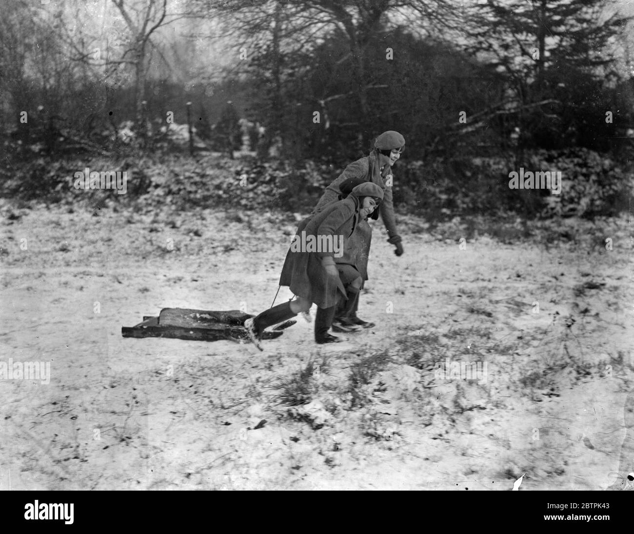 Gute Pull-up! . Zwei Wintersportler ziehen ihren Schlitten zu einem günstigen Ort für den Start einer Abfahrt auf den schneebedeckten Pisten in der Nähe von Welwyn in Hertfordshire. 21 Dezember 1935 Stockfoto