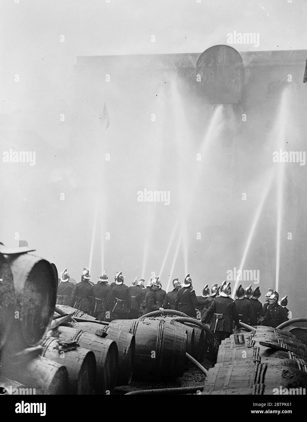 London Rennen Lager Flammen . Carbett ' s Reis Lager in Shad Thames Feuer gefangen und brannte wütend. Foto zeigt, Feuerwehrleute Leitung Schläuche auf das lodernde Gebäude. April 1936 Stockfoto