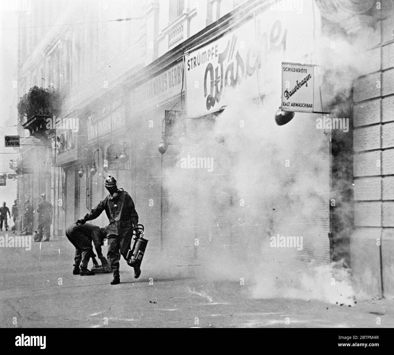 Luftangriff auf Wien . Die von der österreichischen Regierung in Wien organisierte Anti-Luftangriffsübung war die realistischste in der Erinnerung an Wien. "Giftgas" stieg in Wolken, "Bomben" explodierten und Feuerwehrleute und erste-Hilfe-Arbeiter unter den Trümmern von Gebäuden und Fahrzeugen gearbeitet. Foto zeigt, Gas maskierte Polizei mit einem Opfer in Sicherheit 16 September 1935 Stockfoto