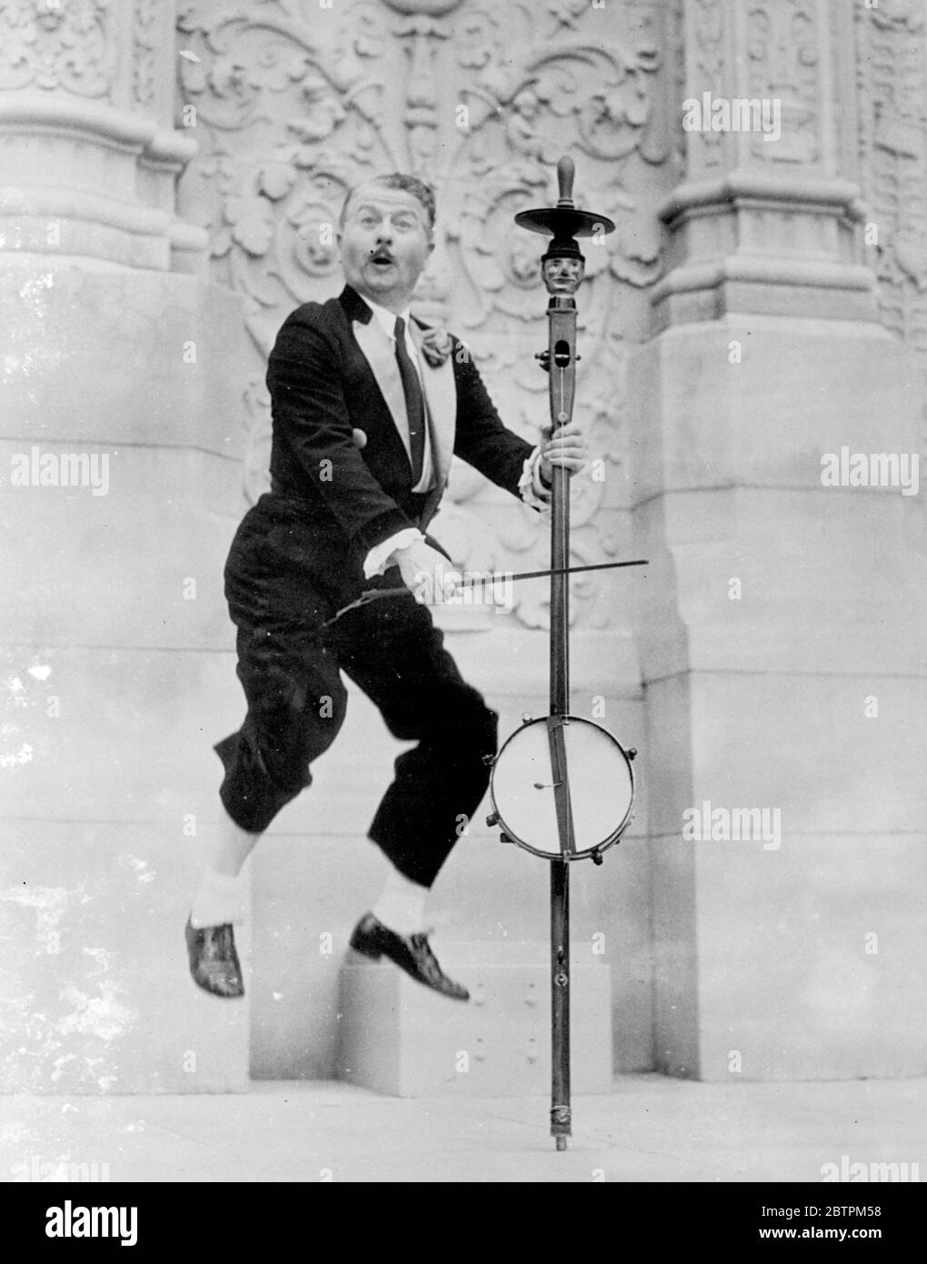 Mid Air Musiker . Neely Edwards , langjähriger Filmkomödiant und wie ein Meister der Zeremonien auf der kalifornischen Pacific International Exposition in San Diego, USA, zieht die Aufmerksamkeit der Massen mit einem neugierigen Musikinstrument seiner eigenen Erfindung. Das Instrument ist eine Kombination aus Trommel, Geige und Pogo Stock durch ein geschnitztes Bild überragt. Der Pogo Stick ist ein Stock mit starken Federn ausgestattet , früher als Spielzeug von amerikanischen Kindern verwendet . Foto zeigt, Neely Edwards demonstriert seine neugierigen Instrument auf der Ausstellung. April 1936 Stockfoto
