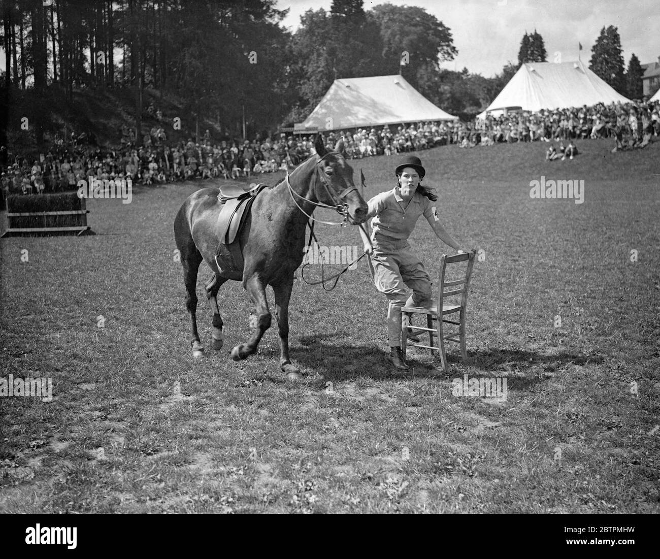 Ihr Anspruch Abstecken ! Foto Zeigt : Als führende Frau poney, eine Reiterin eifrig Anspruch auf einen Stuhl, wie die Musik hört während der Musical Chairs Wettbewerb - eine der vielen Veranstaltungen auf der Haywards Heath Horticultural Society ' s Sommershow in Victoria Park, Haywards Heath, Sussex. Juli 1936 Stockfoto